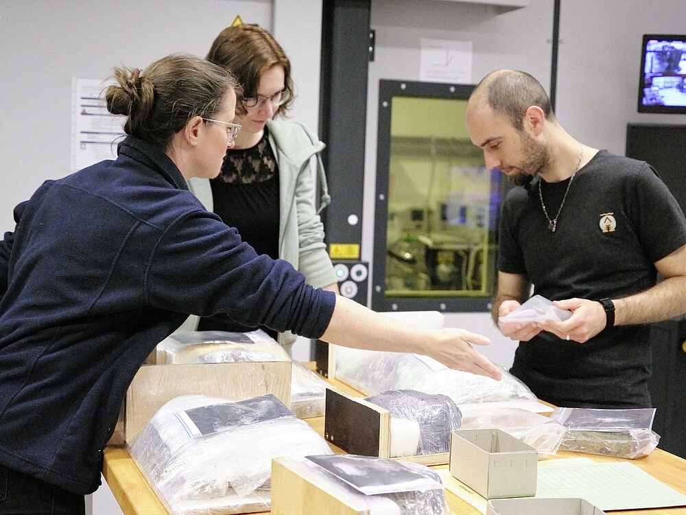Veranstaltungsbild Dr. Ivan Calandra und Dr. Jana Kunze (LEIZA, Mitte und rechts) im Austausch mit Christine Henke (hessenARCHÄOLOGIE, links) zur Untersuchung der Blockbergung.