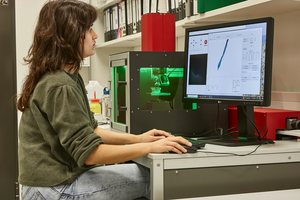 Wissenschaftlerin betrachtet auf einem Bildschirm die Ergebnisse der Computer-gesteuerten Laserstrahl-Untersuchungen